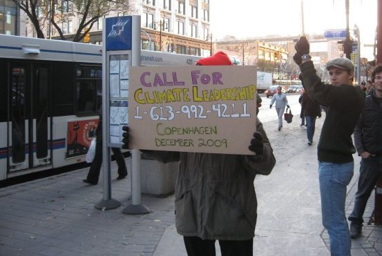Taking "the call" literally: A protester at the International Day of Climate Action holds up a placard with the Prime Minister's phone number.
