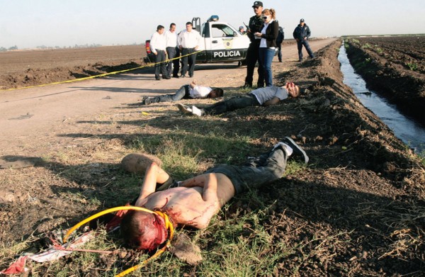 Bodies lie in a ditch in rural Mexico, as police look on. Photo by Tomas Bravo/Reuters