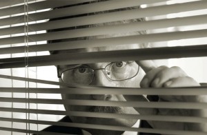Suspicious man peering through blinds