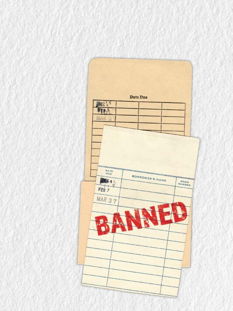 An old-fashioned library card system from the back of a library book is stamped with the word BANNED in all caps